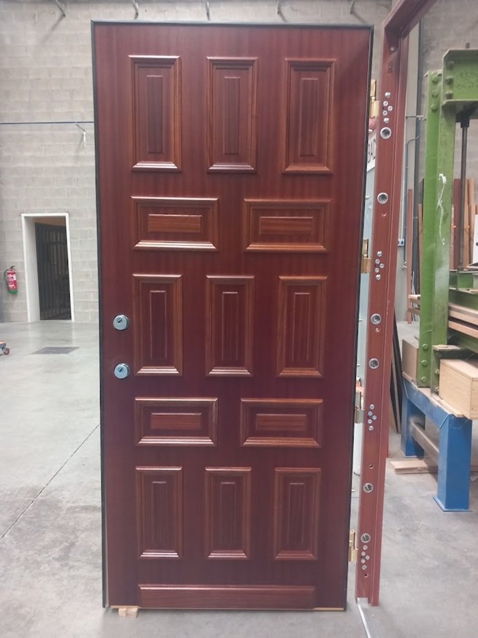 Puerta acorazada CABMA clásica con cuarterones de madera noble y marco de acero en taller